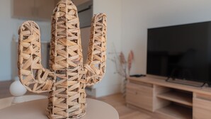 Una escultura de cactus trenzado sobre una mesa en una sala de estar moderna, con televisor de pantalla plana y muebles de madera.