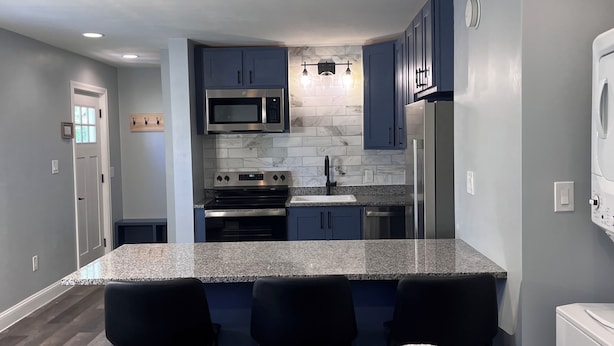Una cocina moderna con encimeras de granito, electrodomésticos de acero inoxidable y armarios azules.