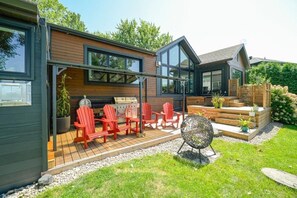 Ein modernes Haus mit Terrasse, Sitzgelegenheiten im Freien und Grillplatz.