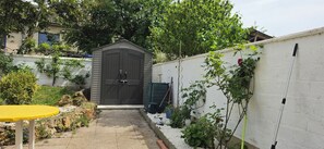 A garden with a shed, a yellow table, and a white wall. - Apartment with garden near Paris (Créteil)
