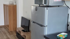 Una cocina compacta con microondas, refrigerador y armarios de madera.