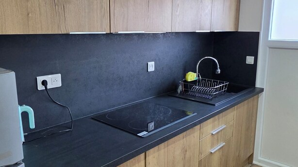 Una cocina moderna con armarios de madera, encimera negra y pileta de acero inoxidable.