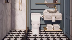 Een badkamer met een marmeren wand, een wit toilet, een douche met een gouden accent en een spiegel, plus een geruit vloertje.