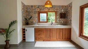 Una cocina con baldosas estampadas, un mueble de madera, un refrigerador empotrado, un ventanal y un colgador de techo.