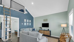 Una sala de estar con sofá, televisor, lámpara y sillón de mimbre.