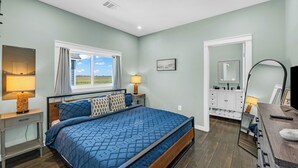 Un dormitorio con cama, lámparas de noche, ventana, cómoda y espejo.
