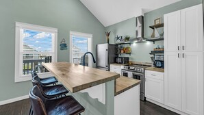 Una cocina con una isla de madera, armarios blancos y vistas a través del ventanal.