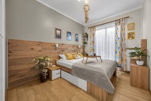 Ein Schlafzimmer mit einem hölzernen Kopfteil, einem Bett mit gemusterten Kissen, einem Nachttisch mit einer Pflanze und einer Nachttischlampe.