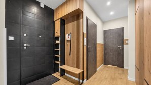 Un pasillo moderno con puertas negras, paneles de madera y un banco.