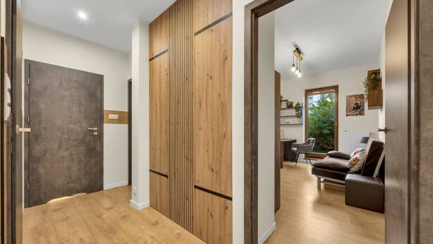 Un interior moderno con suelo de madera, una puerta cerrada y una zona de estar con un sofá y una mesa.