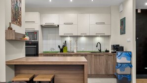 Una cocina moderna con armarios blancos, una isla de madera y un refrigerador negro.