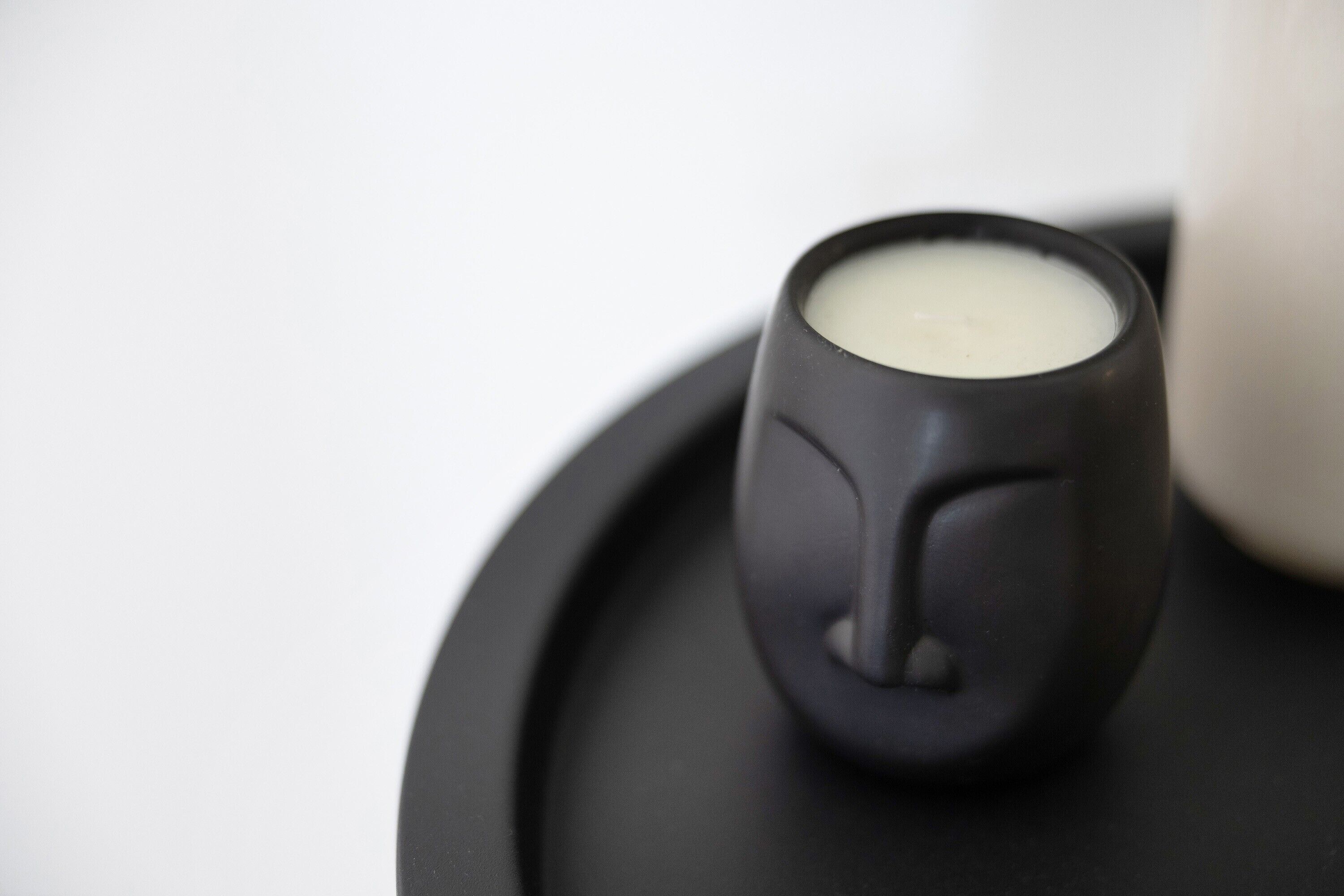 Eine schwarze Keramiktasse mit Henkel auf einem schwarzen Tablett.