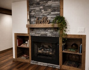 A fireplace with a stone facade, a 'hello' sign above it, and bookshelves on either side. - Barn on the Buffalo Jasper (Jasper)