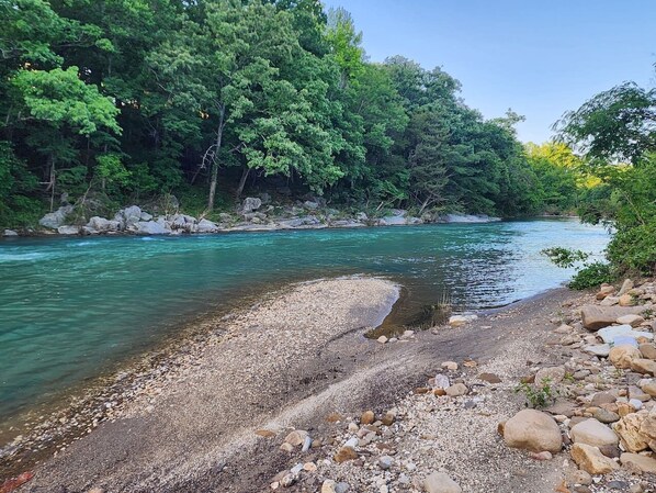 A river with clear water, surrounded by rocks and trees.