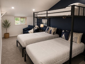 A bunk bed room with two beds, a nightstand with a lamp, a chair, and a potted plant.