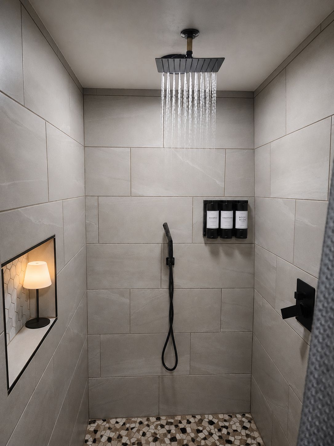 A modern shower with a rain showerhead, a handheld showerhead, and a wall-mounted soap dispenser.
