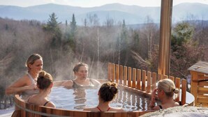 En grupp människor i ett bubbelbad med ett trästaket och en träkonstruktion i bakgrunden.