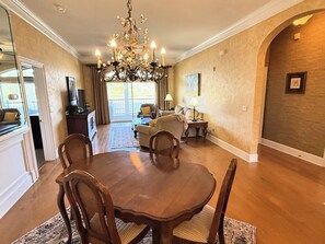 A dining area with a chandelier, wooden dining table, and chairs. - Gated Luxury Condo Overlooking The Intercoastal Waterway  & Centrally Located (Myrtle Beach)