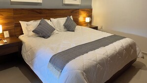 A neatly made bed with a patterned throw, two framed pictures on the wall, and a nightstand with a lamp. - Huatulco Loft 411 PG 5 minutes from El Arrocito Beach (El Arrocito, Huatulco)