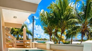 A swimming pool with clear blue water, surrounded by palm trees and a white building with a staircase. - CasaMar Oceanfront House w/ Pool & Master Suite• Rincón (Aguada)