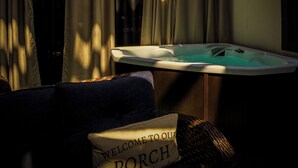 Une chambre avec une baignoire, des rideaux et un coussin orné de l’inscription « BIENVENUE SUR NOTRE PORCHE ».