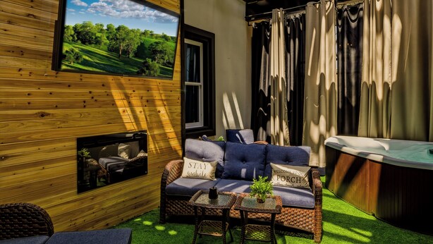 Un espace extérieur accueillant avec un canapé, deux petites tables et un jacuzzi.