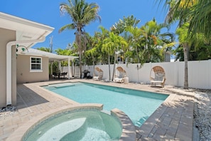 A swimming pool with a hot tub, surrounded by palm trees and lounge chairs. - Sandcastle By The Sea (Holmes Beach)