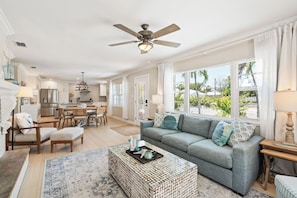 A spacious living room with a grey sofa, a coffee table, and a ceiling fan. - Sandcastle By The Sea (Holmes Beach)