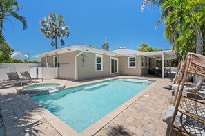 A residential property with a swimming pool, outdoor seating, and palm trees. - Sandcastle By The Sea (Holmes Beach)