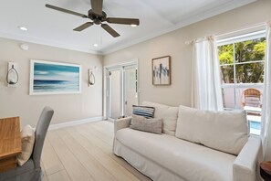 A living room with a ceiling fan, a sofa, a table, and a chair. - Sandcastle By The Sea (Holmes Beach)