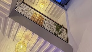 Un tragaluz con diseño de cuadrícula, una celosía metálica decorativa y una lámpara colgante.