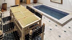 Un espacio interior amplio con piscina, muebles de madera y plantas en macetas.