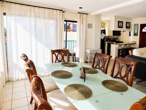 Un espace repas avec une table en verre, des chaises en bois et une vue sur l’extérieur.