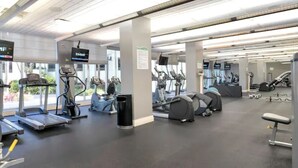 Et fitnesscenter med løbebånd, crosstrainere og styrkeudstyr.