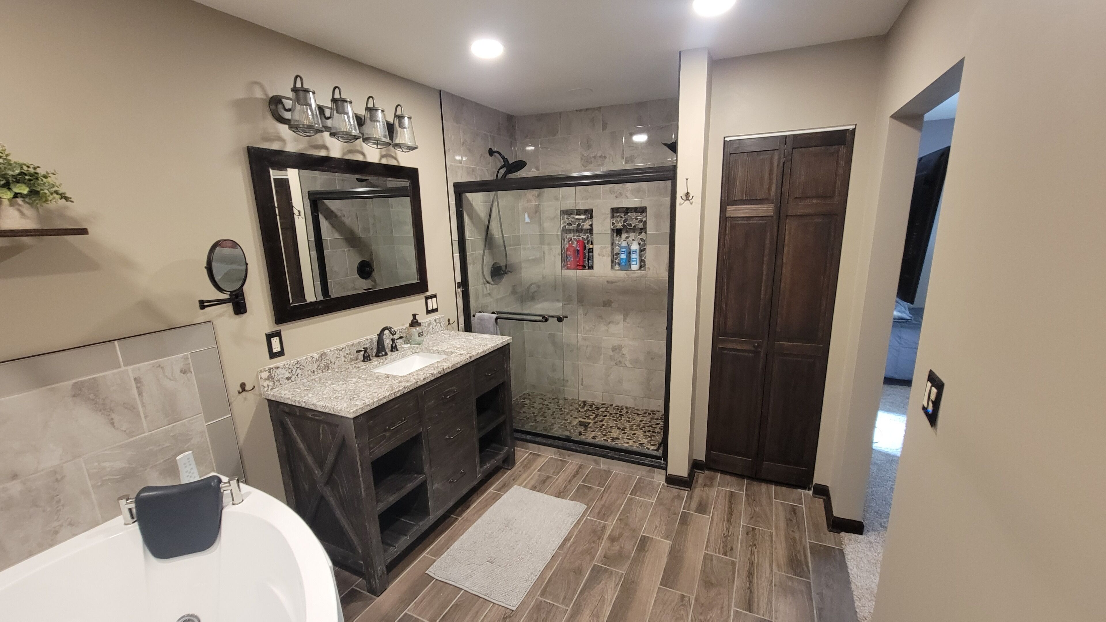 Un baño moderno con bañera, tocador con lavabo, ducha con puertas de vidrio y un espejo grande.