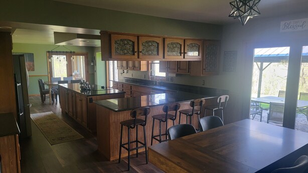 A kitchen with a central island, wooden cabinets, and a bar area. - Stunning 5-bedroom home on 18 acres with complete privacy, seclusion and nature (Burlington)