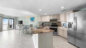 A modern kitchen with a large island, stainless steel appliances, and a dining area with a view. - Beautiful beach condo at Regatta Condominiums. 2 BR/2BA, Sleeps up to 6 adults. (Gulf Shores)