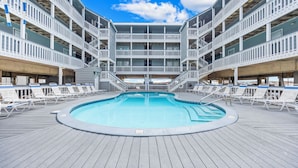 A pool area with multiple levels of balconies, a central pool, and a wooden deck. - Beautiful beach condo at Regatta Condominiums. 2 BR/2BA, Sleeps up to 6 adults. (Gulf Shores)