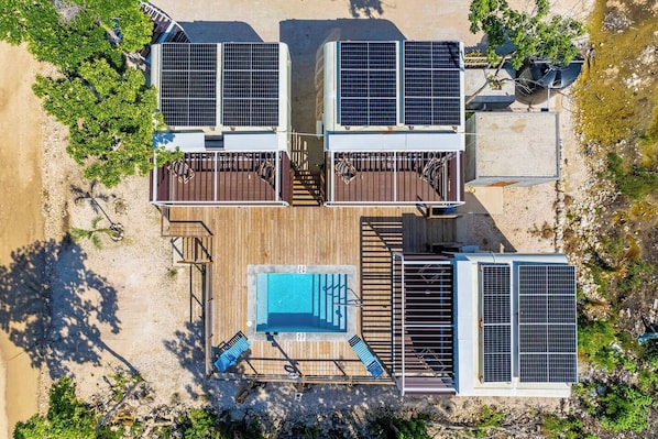 Una azotea con paneles solares, una piscina y una terraza de madera.