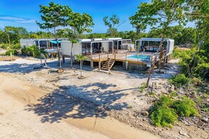 Varias casas móviles con piscinas exteriores, rodeadas de árboles y un sendero de tierra.