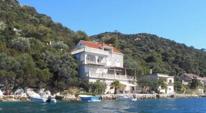 A coastal building with a red roof, white walls, and a balcony. - Apartment Riva - Two Bedroom Apartment with Sea View (1) (Lastovo)