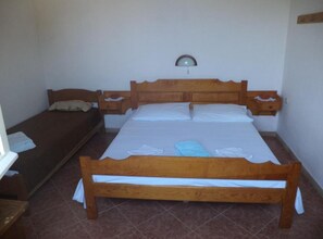 A single bed with a wooden frame, a nightstand with a lamp, and a smaller bed in the corner. - Apartment Riva - Two Bedroom Apartment with Sea View (1) (Lastovo)