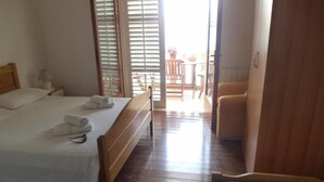 Une chambre à coucher comprenant un lit, une table de chevet, une chaise et donnant sur un espace extérieur.