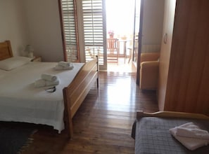 A bedroom with a bed, a bedside table, a chair, and a view of an outdoor area. - Studio Apartment with Terrace and Sea View (2) (Lastovo)