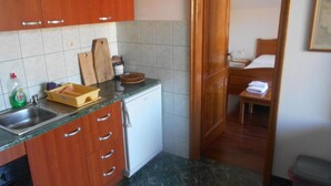 Una cocina compacta con armarios de madera, un lavamanos y un refrigerador pequeño.