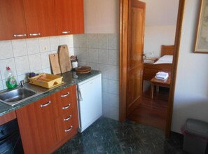 Eine kleine Küche mit Holzausstattung, einer Spüle und einem kleinen Kühlschrank.