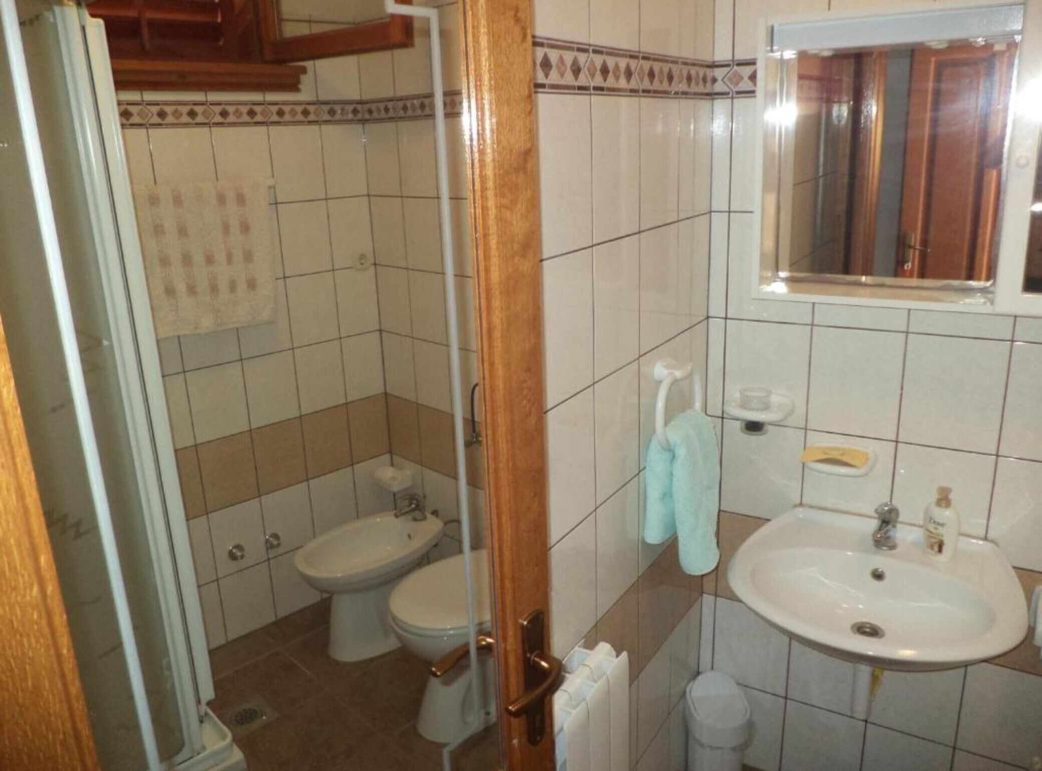 A bathroom with two toilets, a sink, a mirror, and a towel rack.