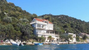 A coastal building with a red roof, white walls, and a balcony. - Studio Apartment President - One Bedroom Apartment with Terrace and Sea View(5) (Lastovo)