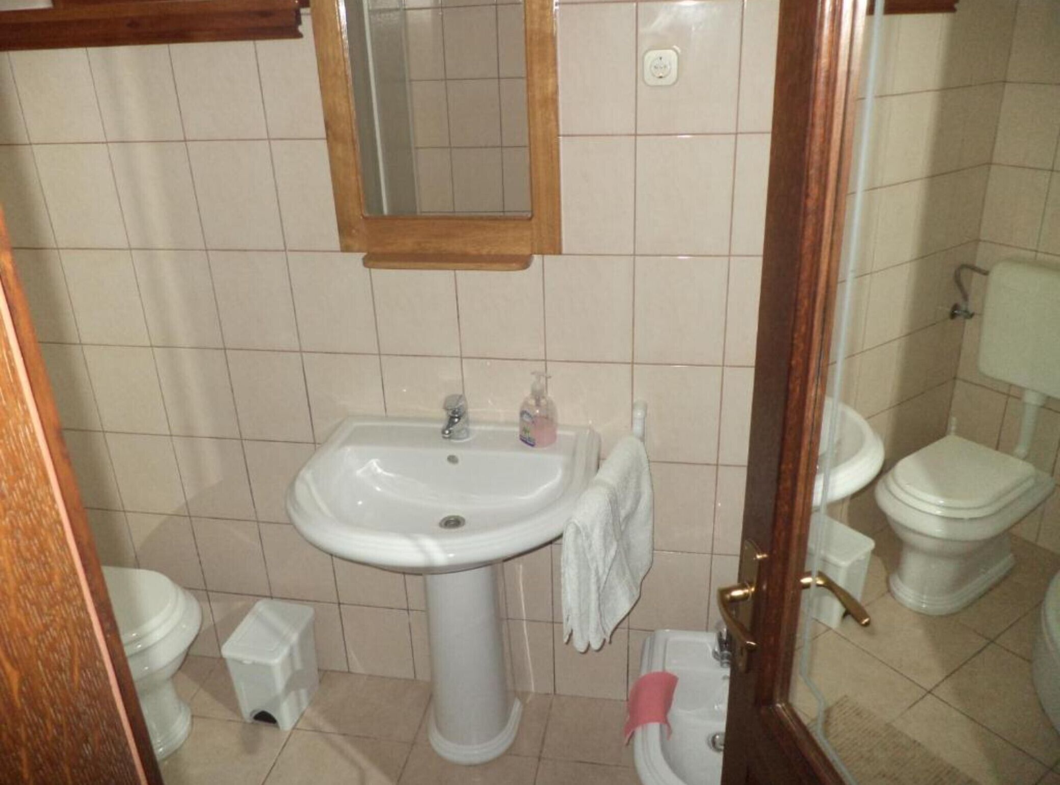 Ein Badezimmer mit einem Waschbecken auf Fußbodenständer, einem Spiegel, einer Toilette und einem Bidet.