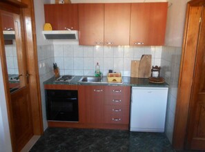 Una cucina compatta con mobili in legno, forno integrato, lavastoviglie e un piano di lavoro con lavello.